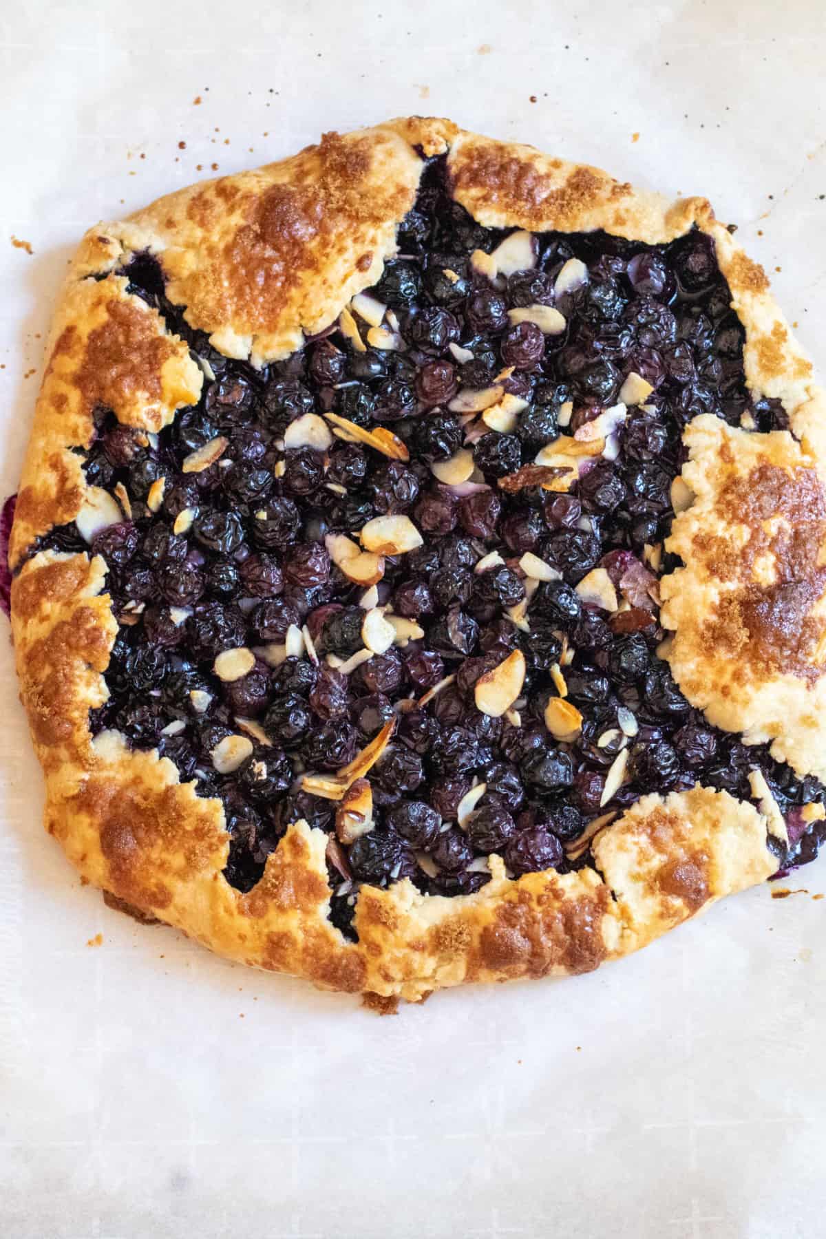 an overhead of a baked blueberry galette with almonds.