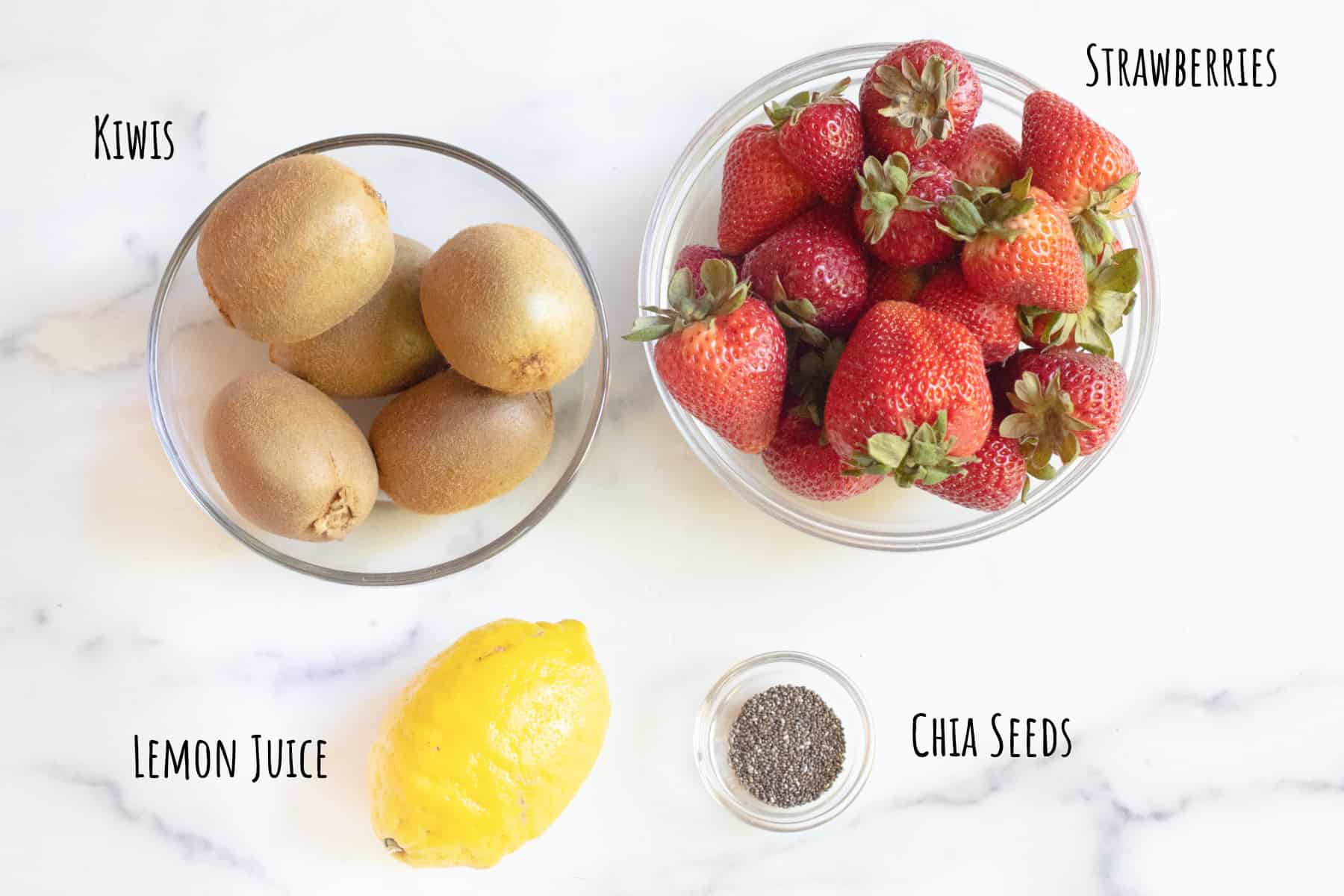 a bowl of kiwis, strawberries, a lemon, and a small bowl of chia seeds.