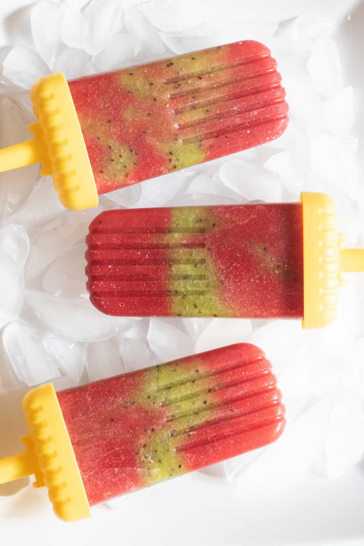 a plate of strawberry kiwi popsicles.