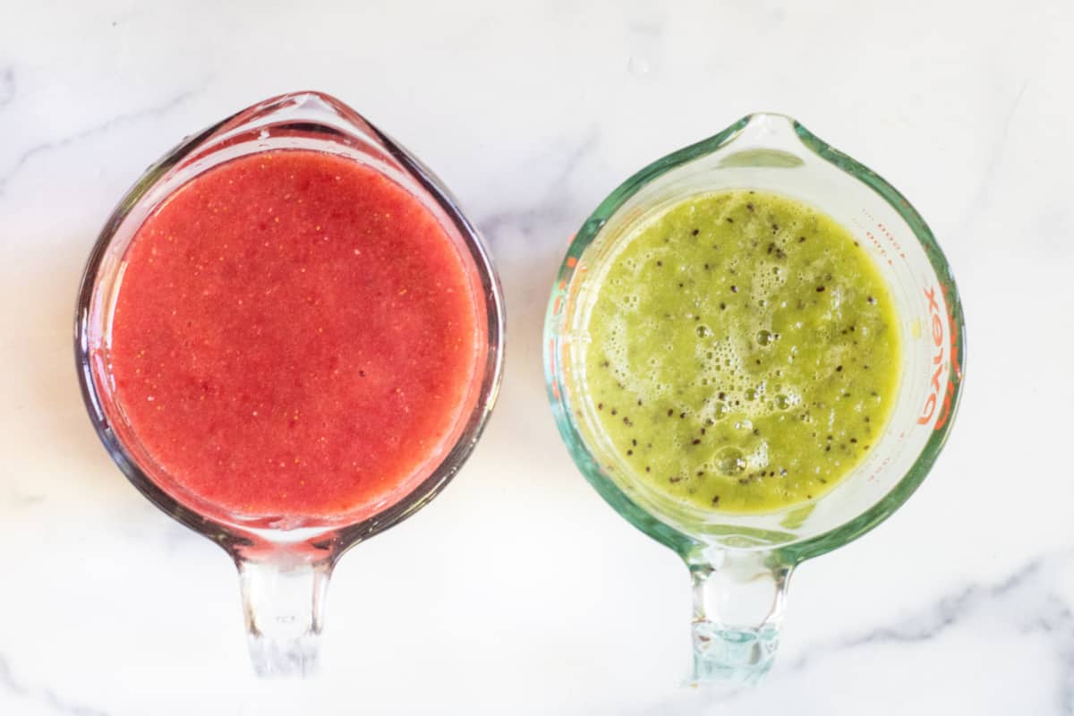 an overhead of two Pyrex measuring cups with strawberry sauce and kiwi sauce in each.