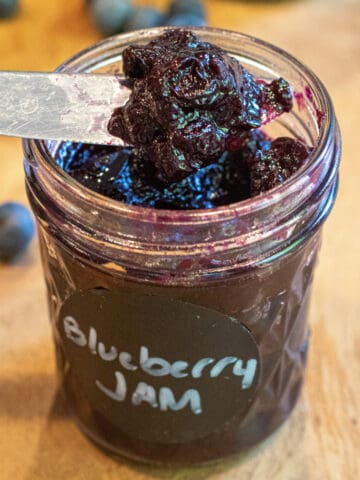 a mason jar labeled Blueberry jam and a knife taking some out.