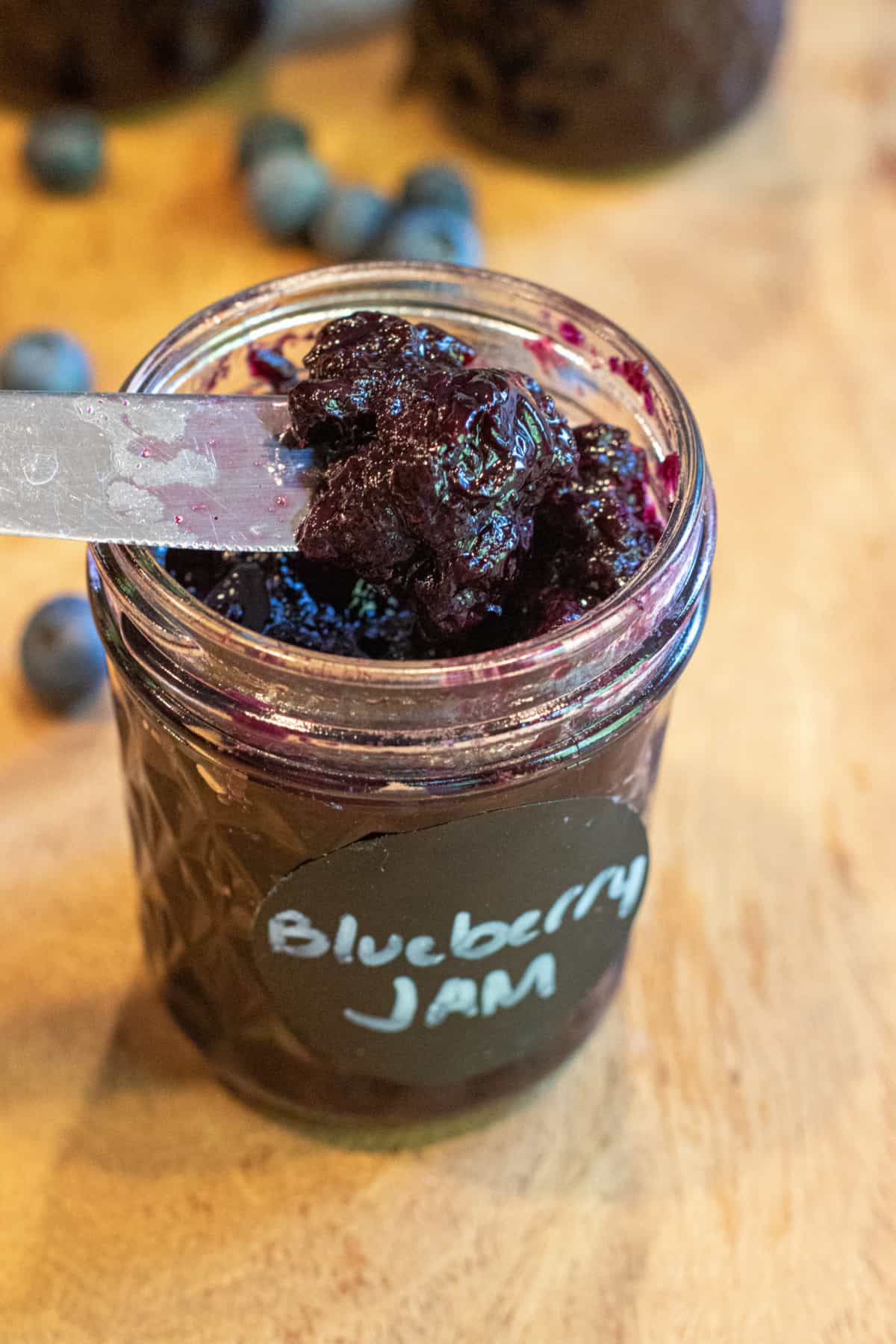 a mason jar labeled Blueberry jam and a knife taking some out.