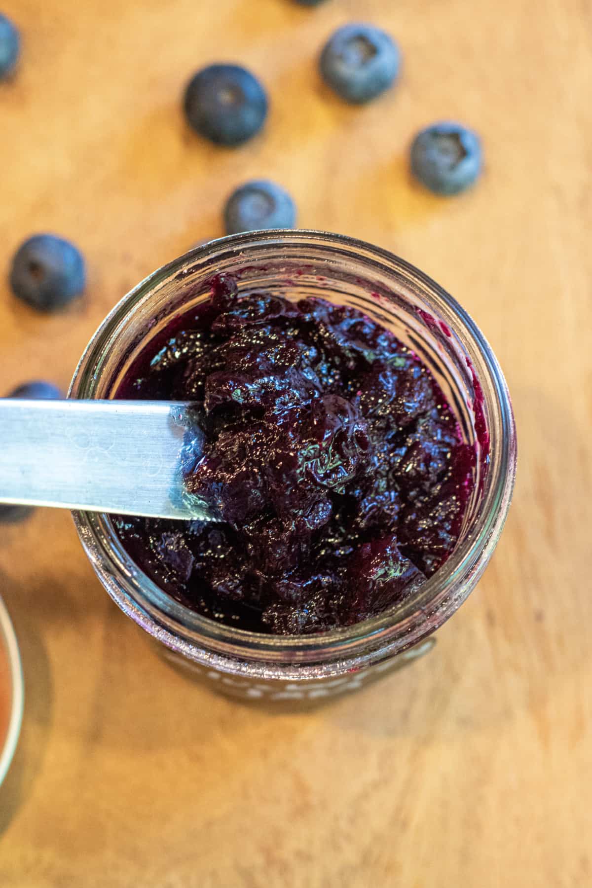 an overhead of an open jar of jam and a knife.
