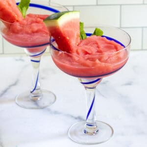 two cocktail glasses of frozen daiquiri with watermelon and mint.
