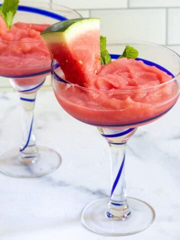 two cocktail glasses of frozen daiquiri with watermelon and mint.