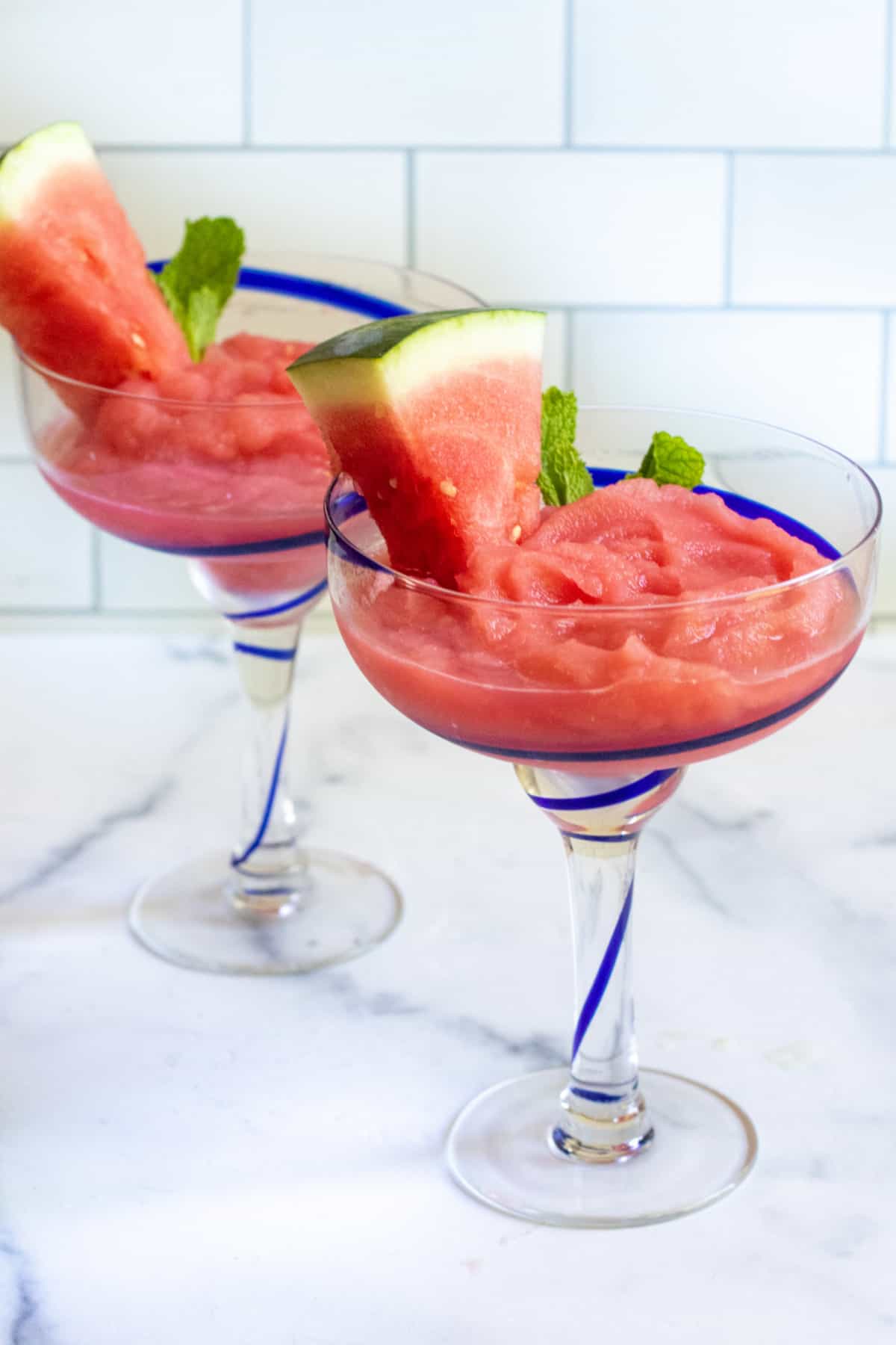 two cocktail glasses of frozen daiquiri with watermelon and mint.