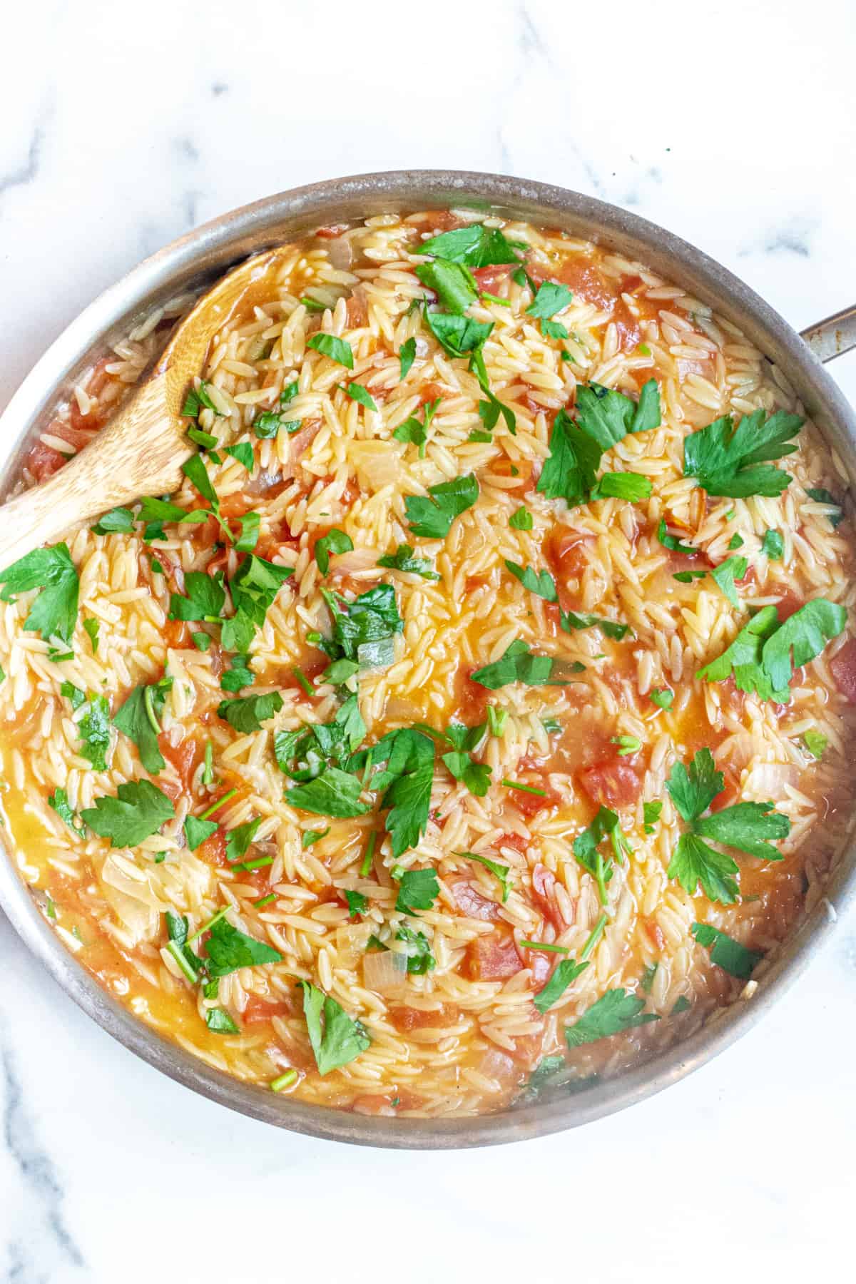 a pot of orzo with tomatoes, cheese, and parsley.