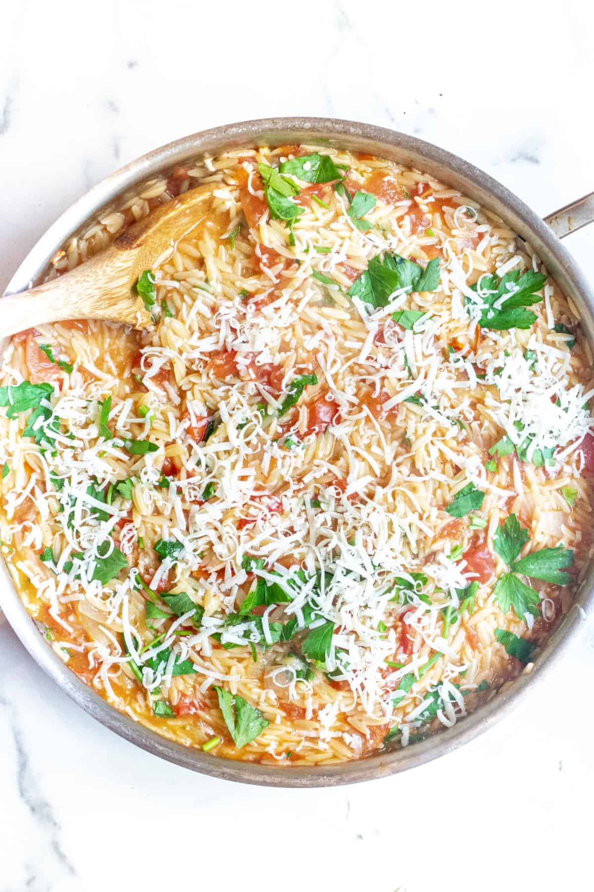 a pot of orzo with tomatoes, cheese, and parsley.