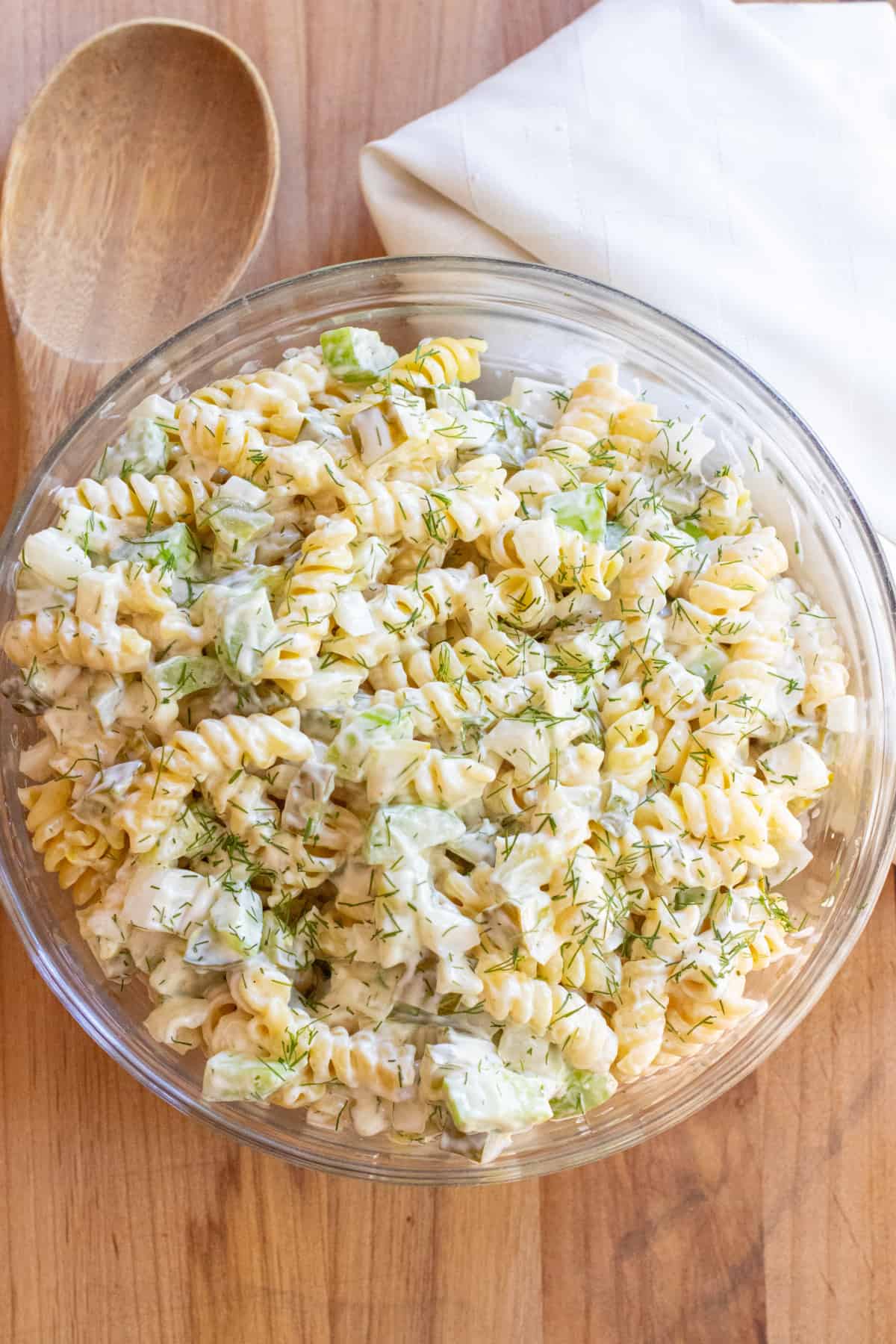 an overhead bowl of rotini pasta salad with celery and dill pickle.