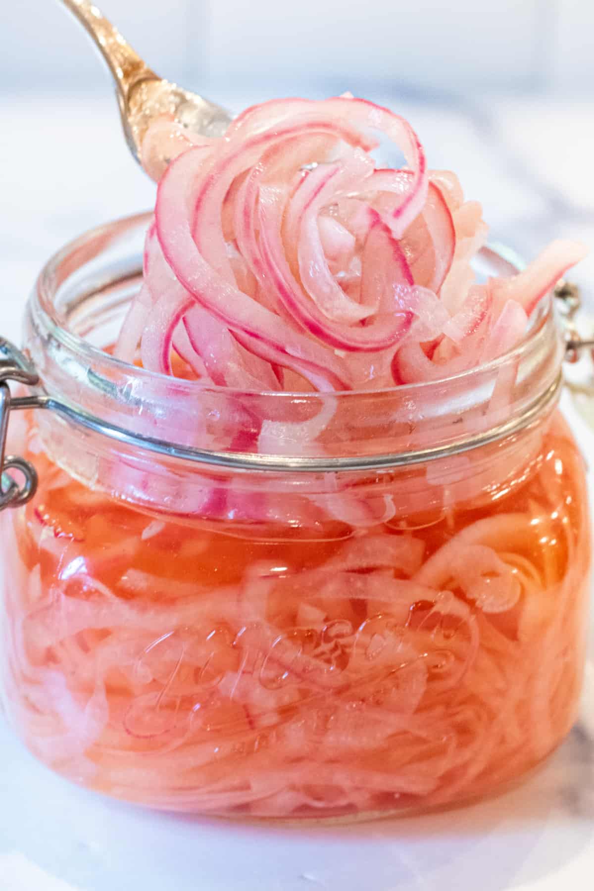 a mason jar of pickled onions with a fork pulling some out.