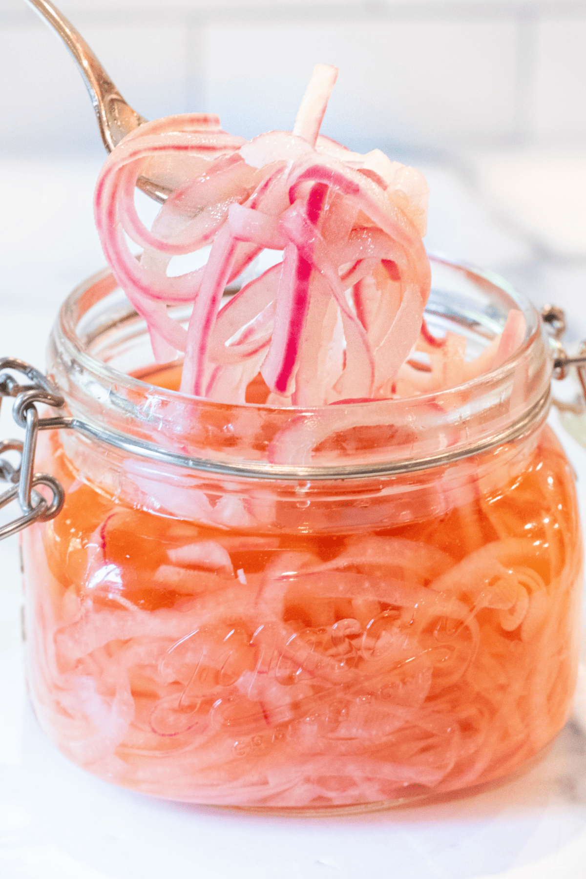 a mason jar of pickled onions with a fork pulling some out.