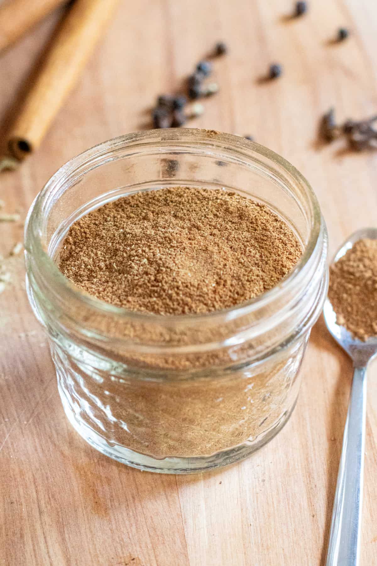 a small mason jar with diy chai and spoon of it next to it.