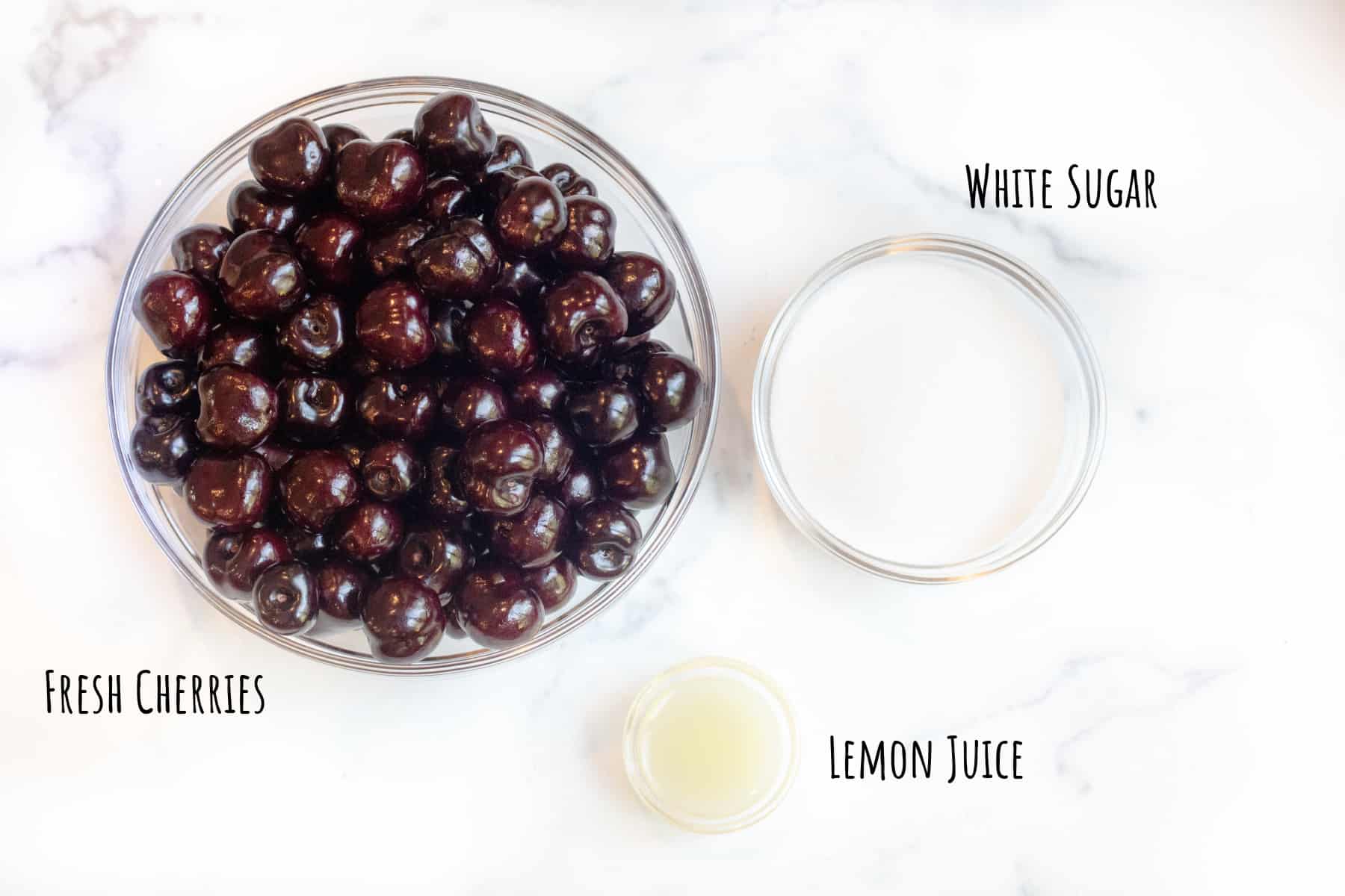 a large bowl of cherries with a bowl of sugar and lemon juice.