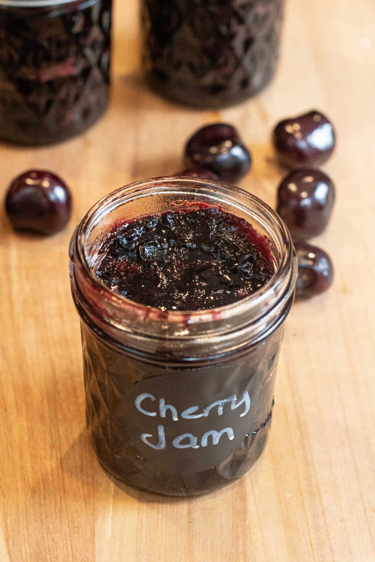 an open jar of labeled cherry jam.