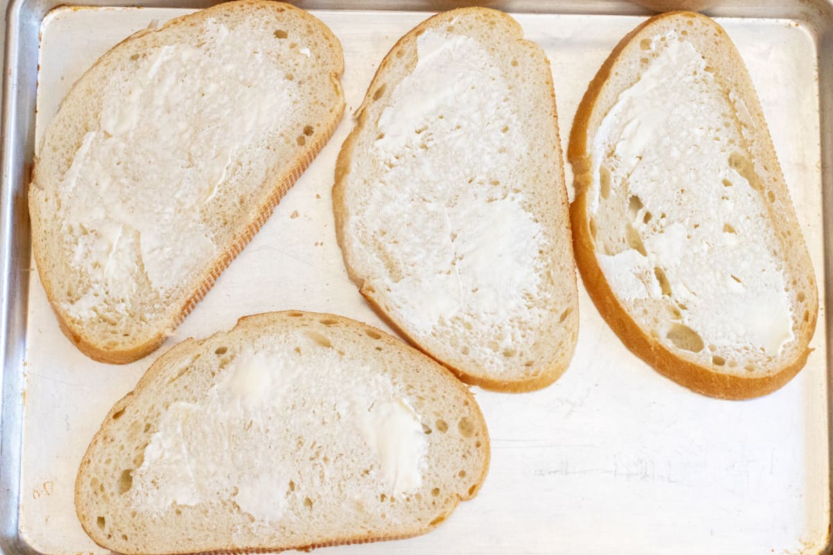 a tray of large slices of bread buttered.