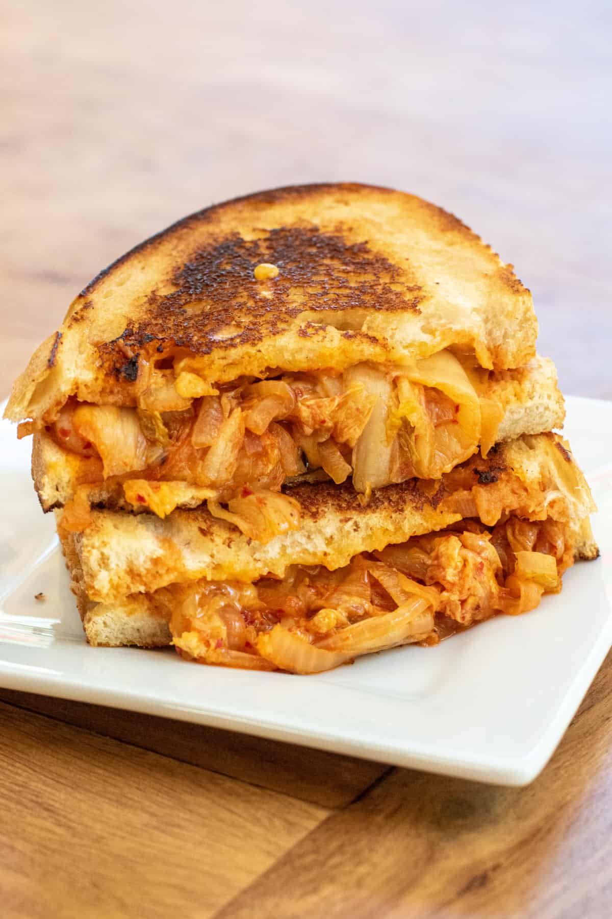 a stacked grilled cheese with onions and kimchi on a plate.