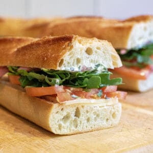a baguette sandwich with tomato and arugula.