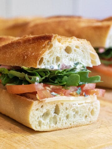 a baguette sandwich with tomato and arugula.