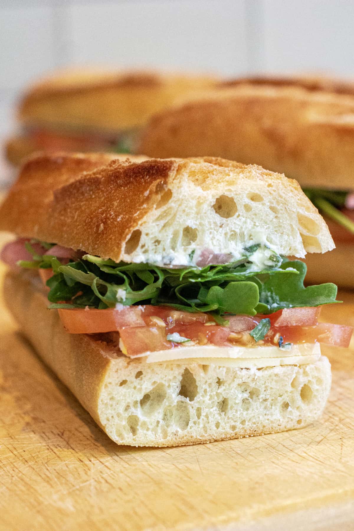 a baguette with arugula with tomatoes and cheese.
