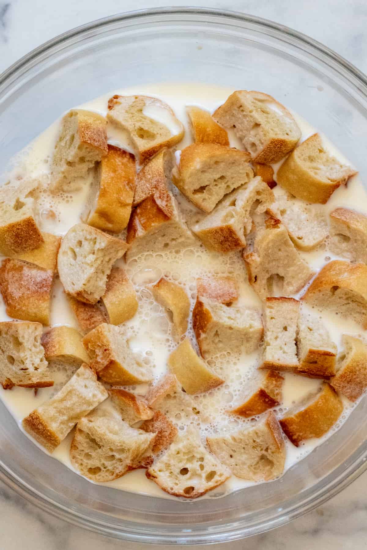a bowl of bread cubes soaking in milk.