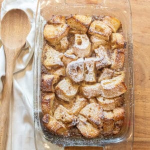 an overhead of a pan of bread pudding next to a wooden spoon.