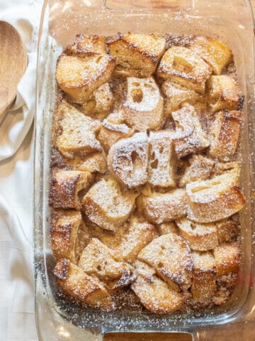 an overhead of a pan of bread pudding next to a wooden spoon.