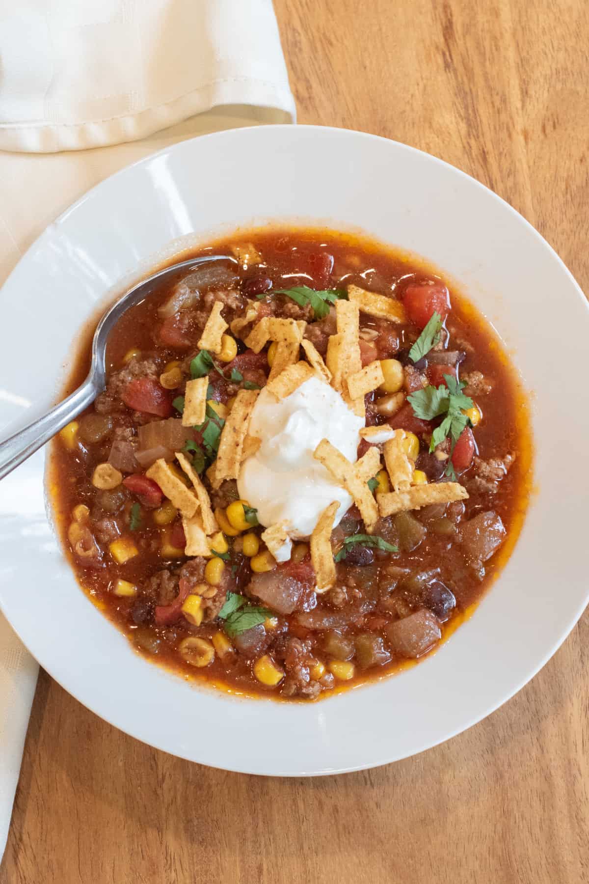 a bowl of taco soup with sour cream and tortilla strips.