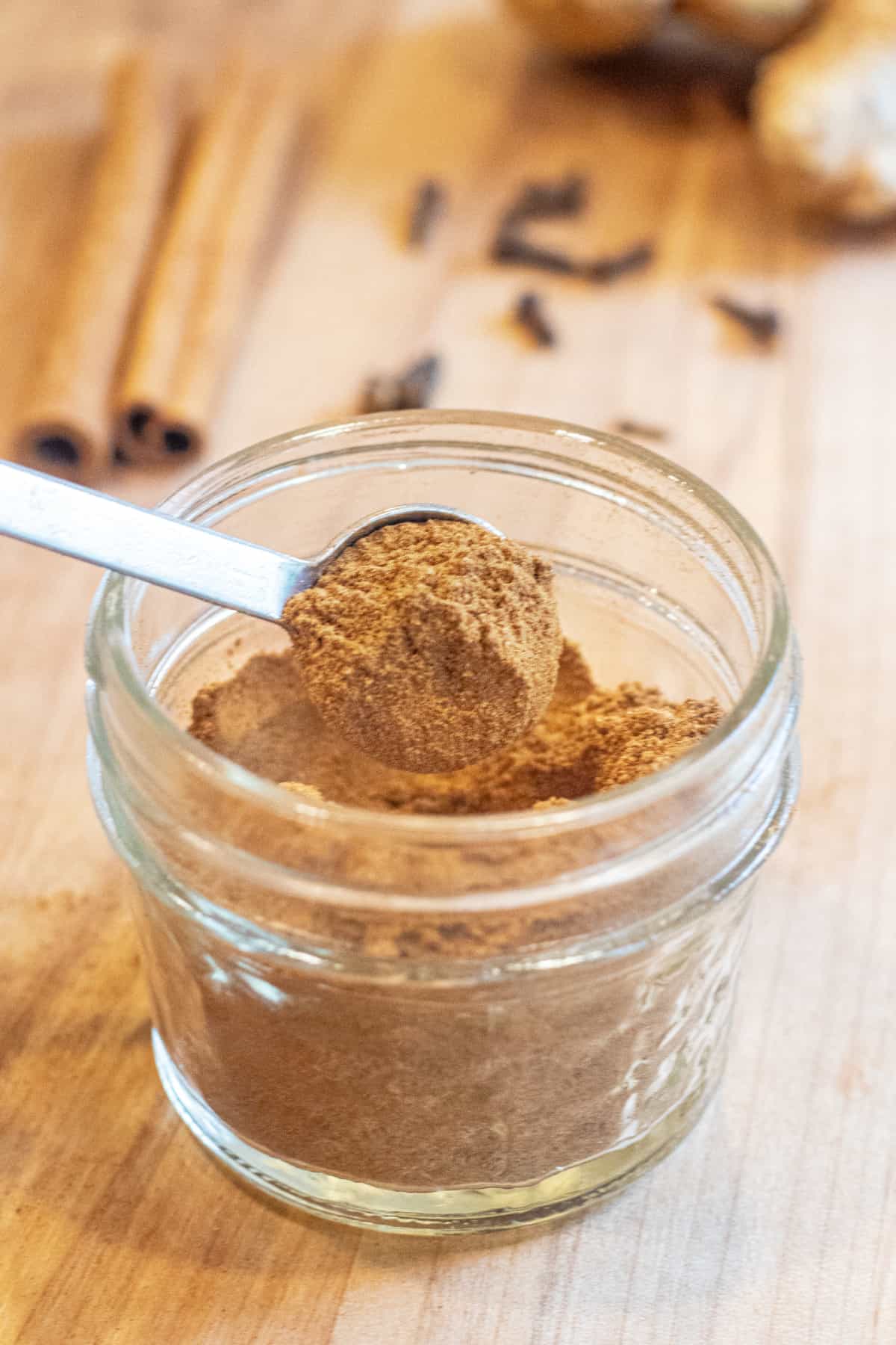 a small mason jar with a measuring spoon with some pumpkin pie spice.