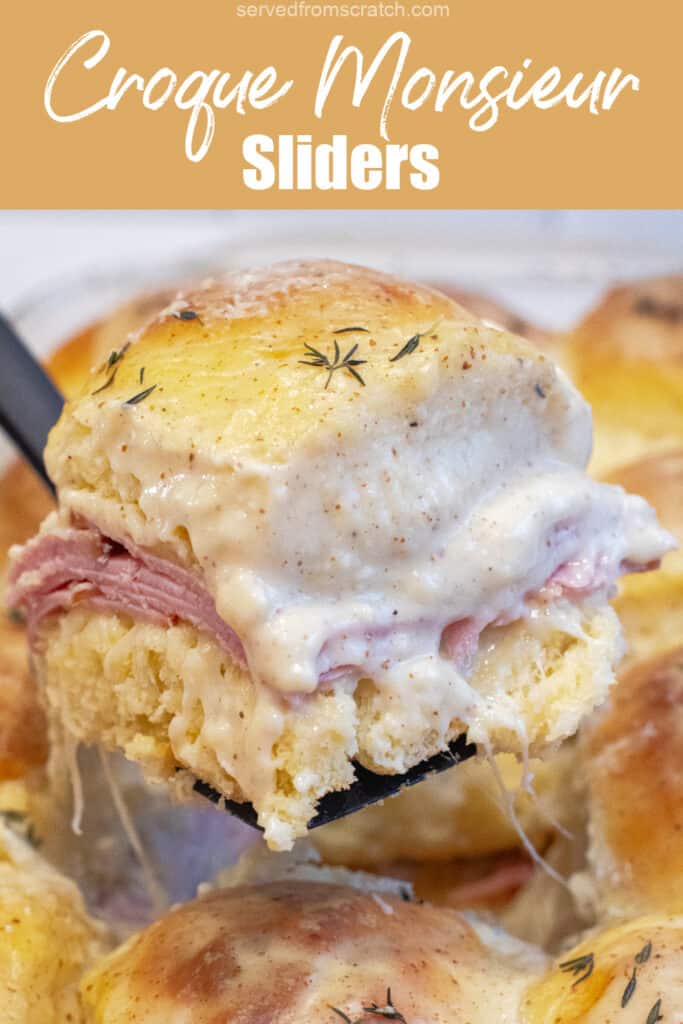 a slider with ham and bechamel sauce being held up in a pan of them with Pinterest pin text.