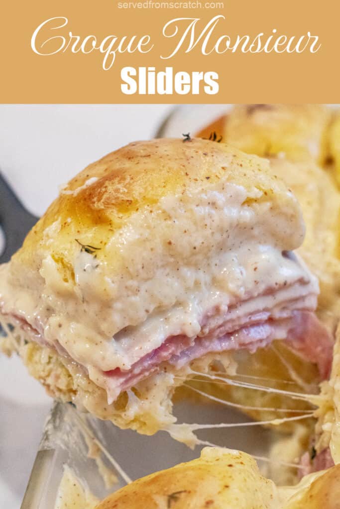 a slider with ham and bechamel sauce being held up in a pan of them with Pinterest pin text.