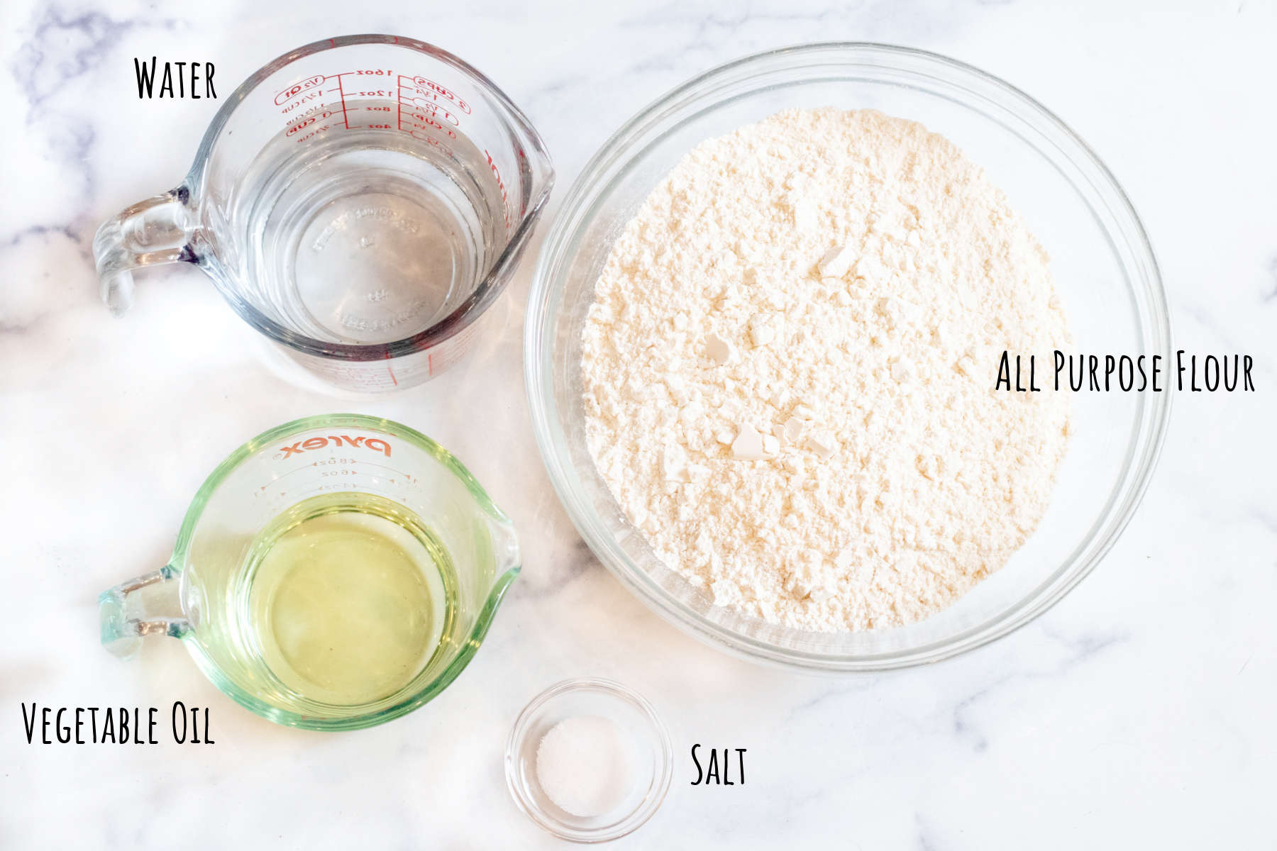 a bowl of flour and Pyrex of water, oil, and salt labeled on a counter.