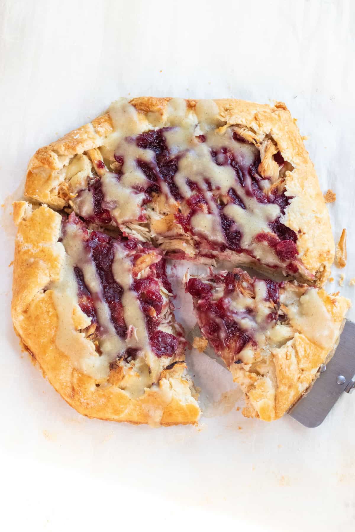 a slice of a cranberry, turkey, mashed potatoes and gravy galette with a slice being take out.