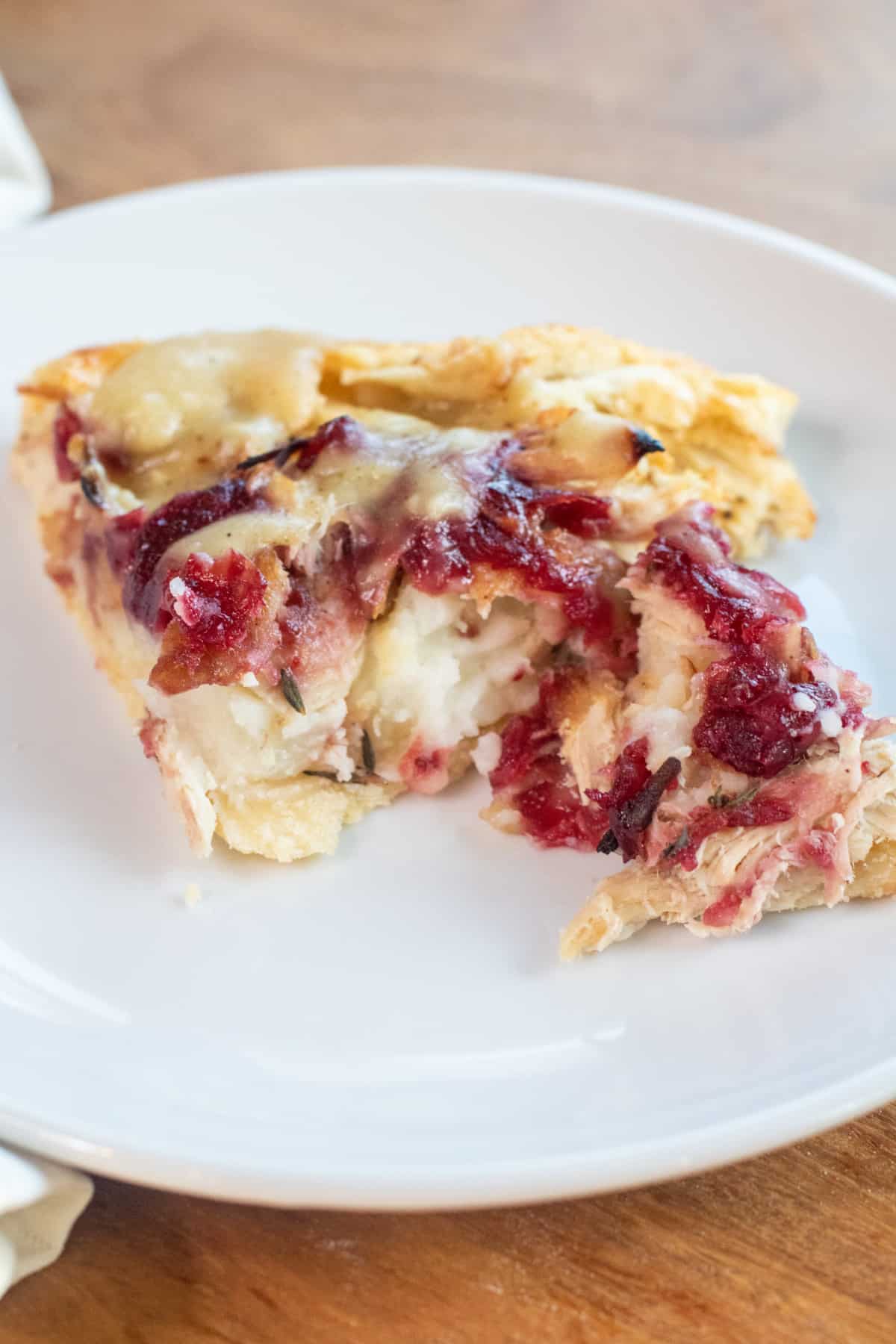 a plate with a piece of savory galette with mashed potatoes, turkey, and cranberries.