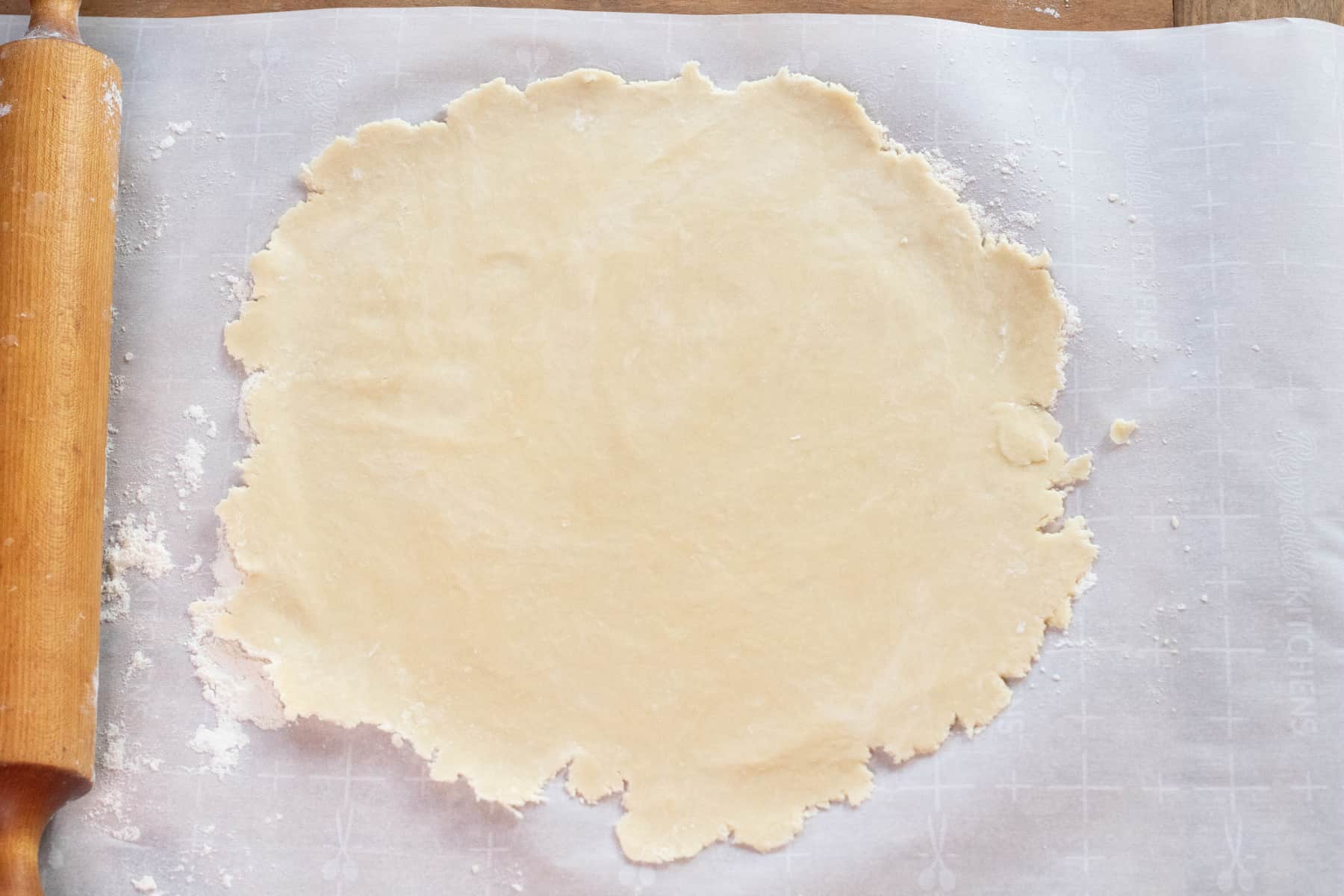 rolled out dough on parchment paper in a rough circle. 