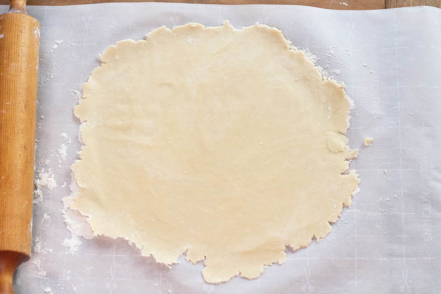 rolled out dough on parchment paper in a rough circle.