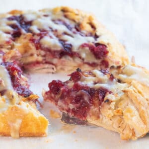 a slice of a cranberry, turkey, mashed potatoes and gravy galette with a slice being take out.