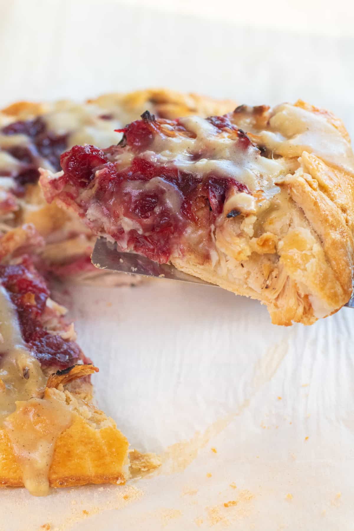 a slice of a cranberry, turkey, mashed potatoes and gravy galette with a slice being take out.