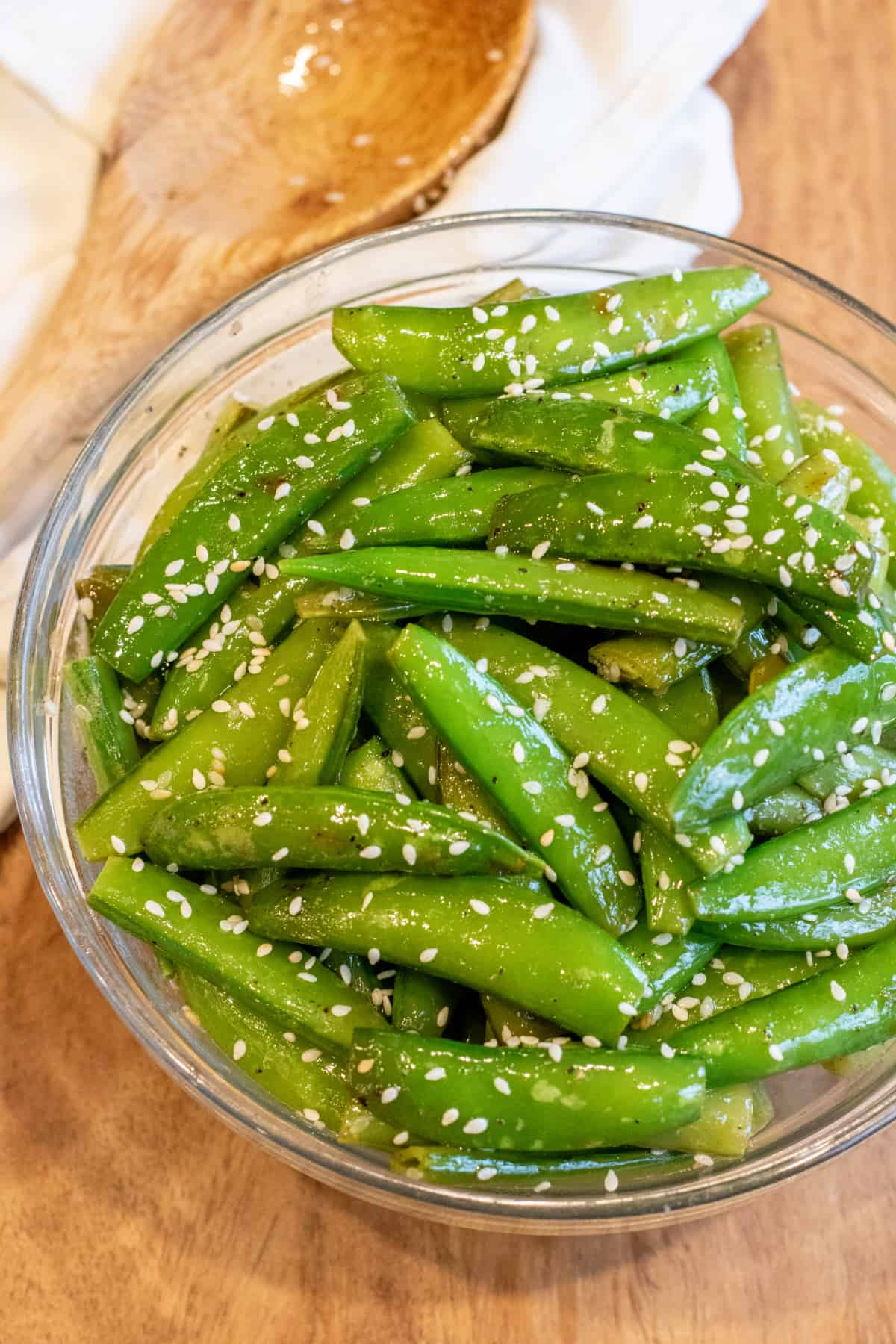 a bowl of sesame seed covered cooked sugar snap peas.