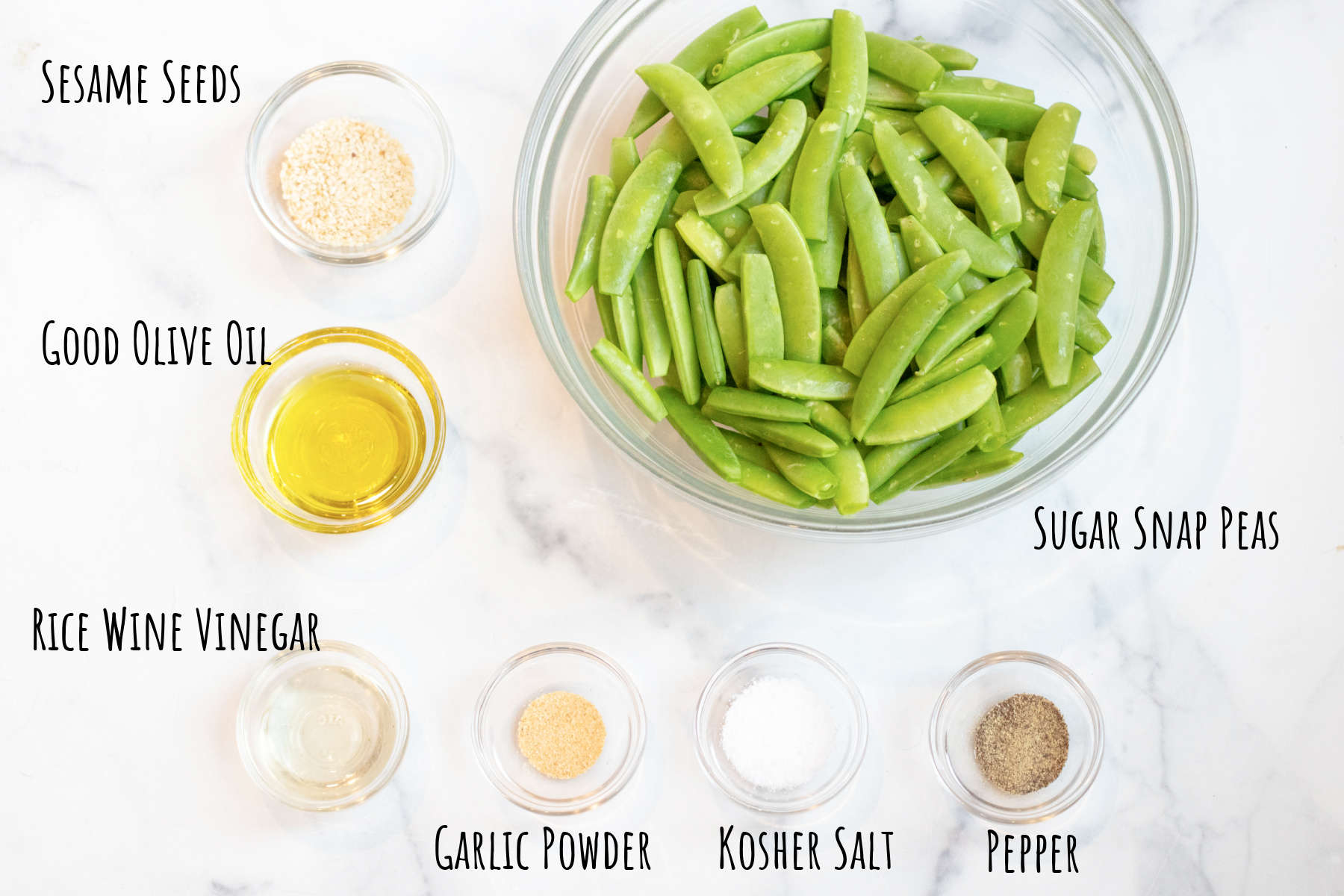 a bowl of sugar snap peas, and then little bowls of sesame seeds, oil, vinegar, garlic powder, salt, and pepper all labeled.