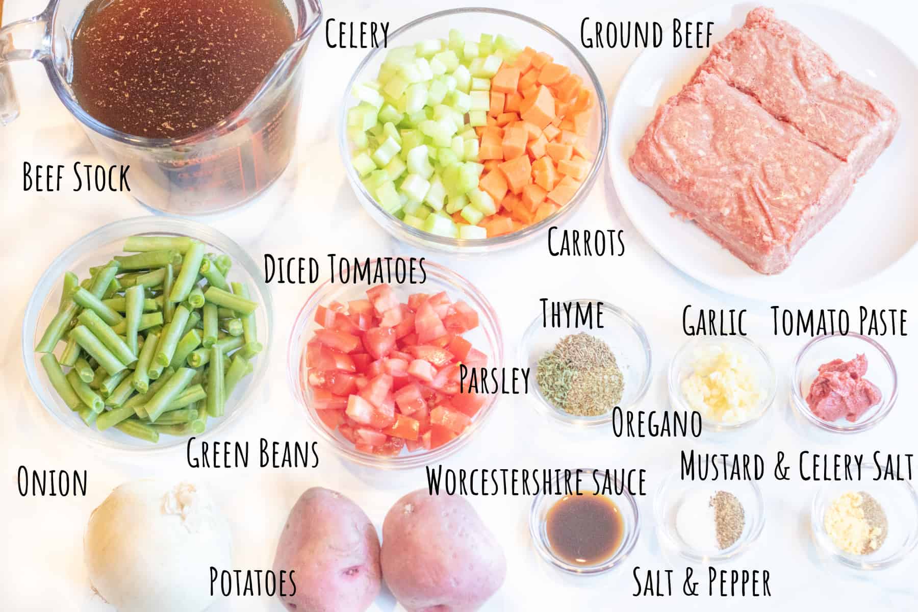 ground beef, stock, celery and carrots, onion, green beans, diced tomatoes, tomato paste, spices, potatoes, and sauce in little bowls.