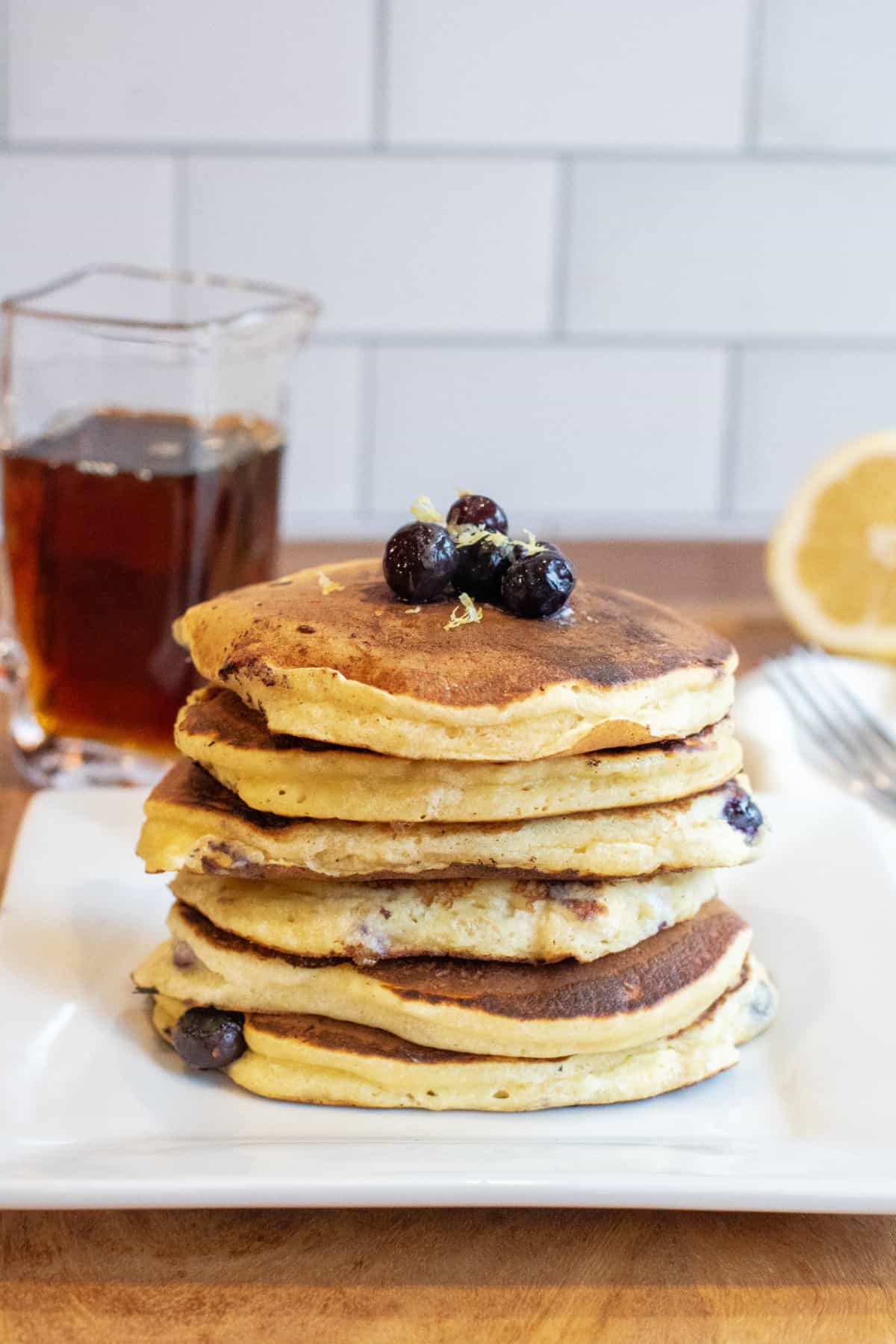 a stack of pancakes with blueberries and lemon zest.