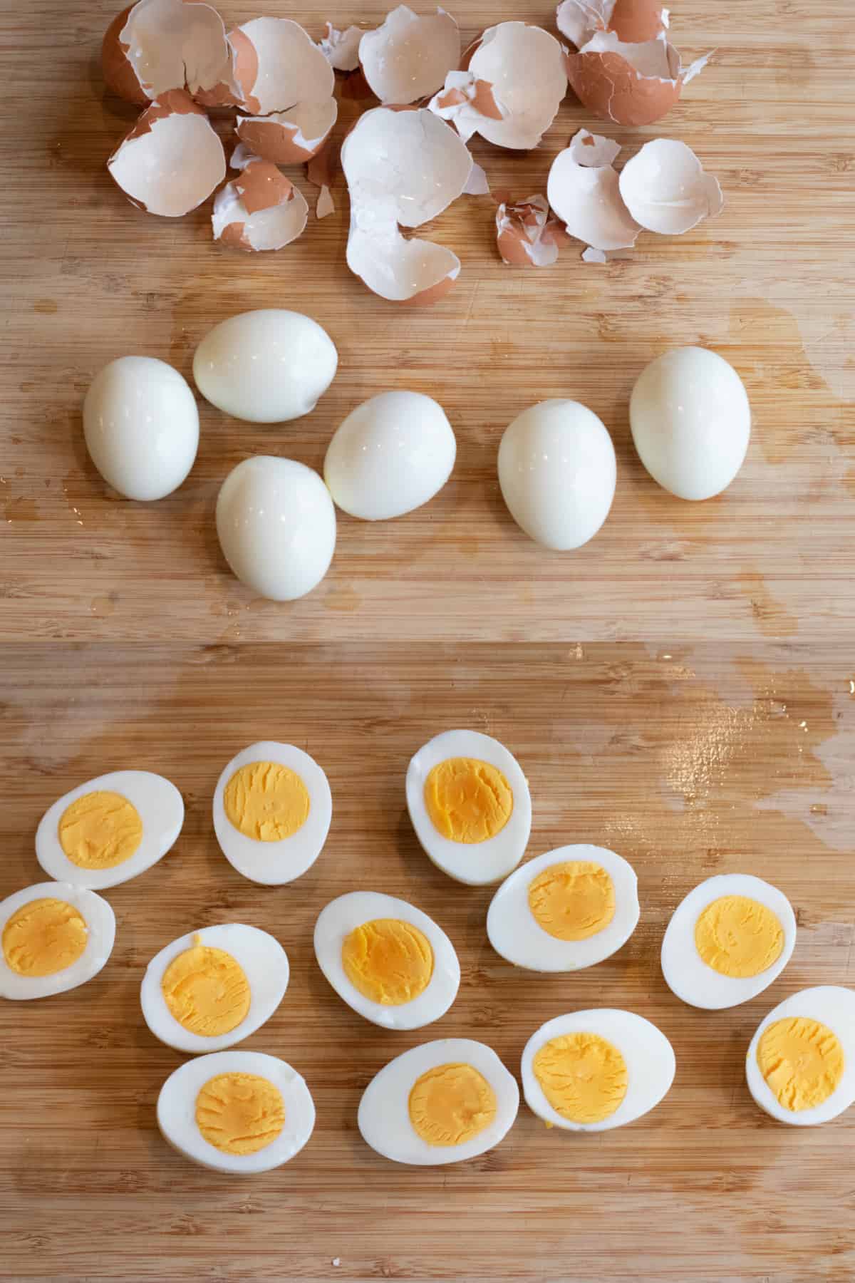 a cutting board of peeled hard boiled eggs and then the eggs cut in half.