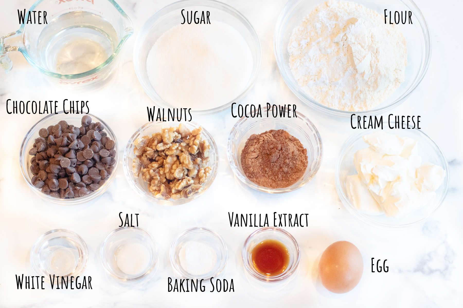 water, sugar, flour, chocolate chips, walnuts, cocoa powder, cream cheese, vinegar, salt, baking soda, vanilla extract, and an egg.