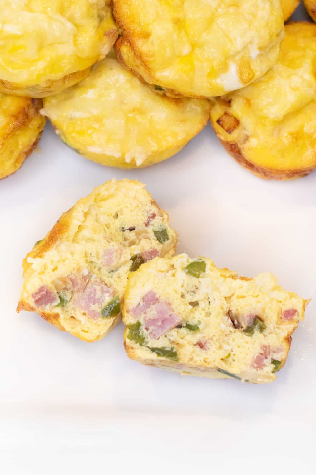 an overhead of a halved egg cup with ham and peppers on a plate.