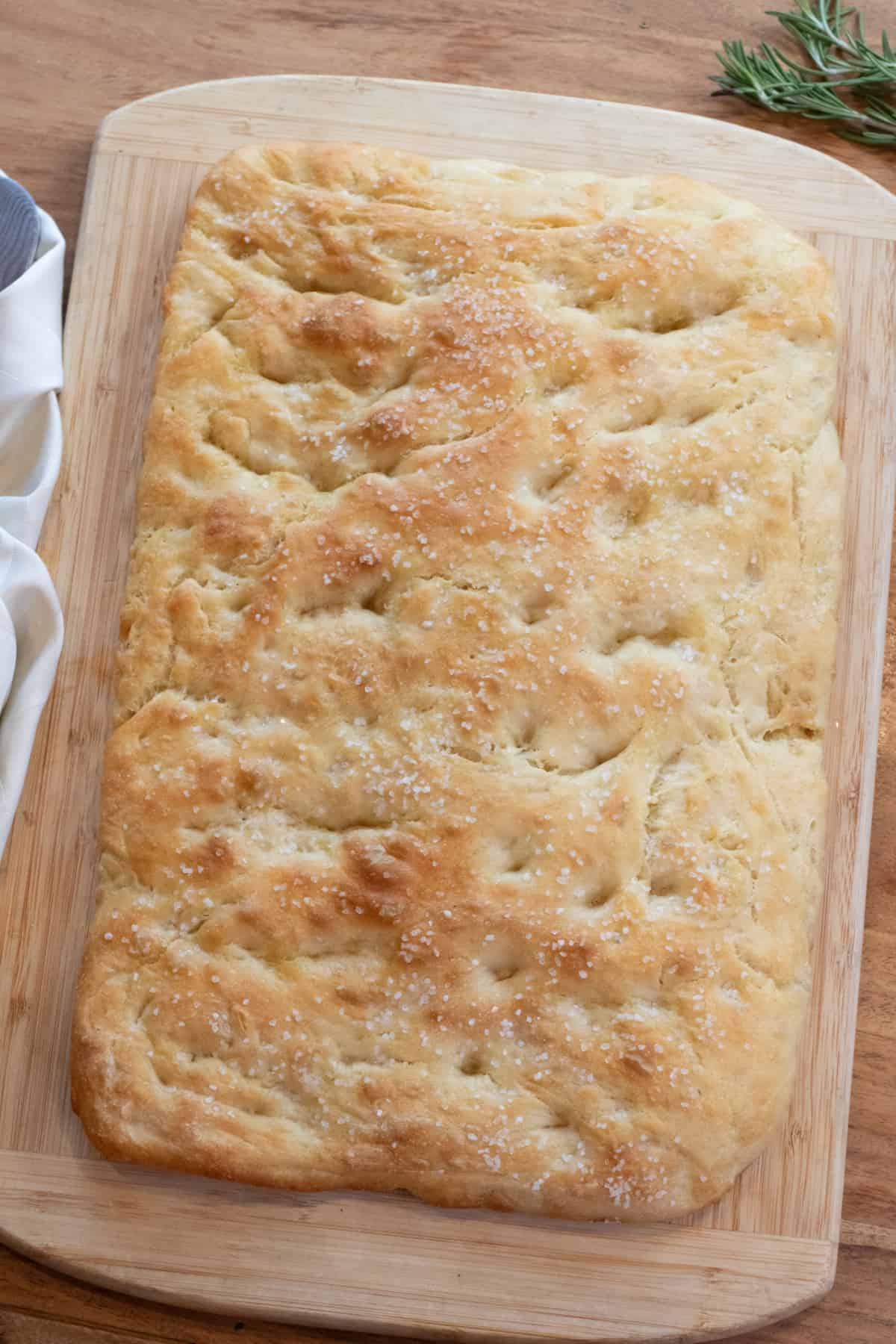 an overhead of a baked focaccia on a cutting board.