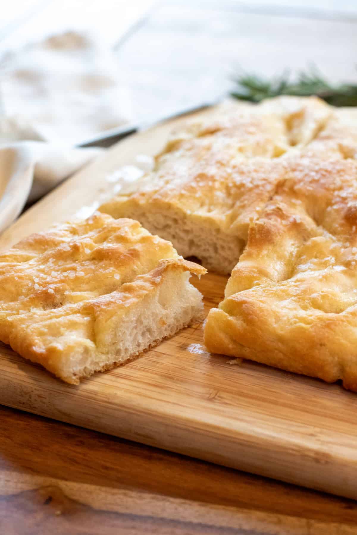 a focaccia on a cutting board with a piece cut out.