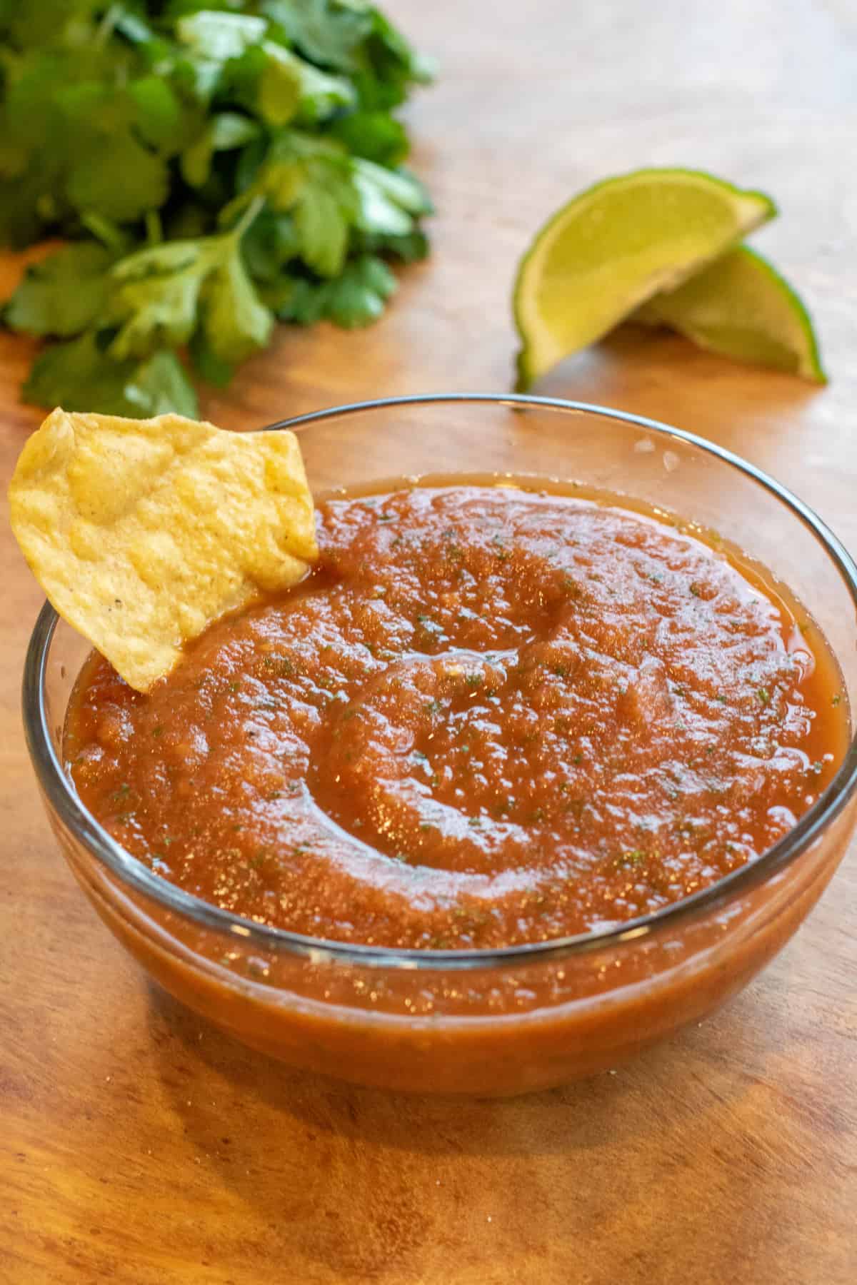 a bowl of smooth tomato salsa with a chip in it.