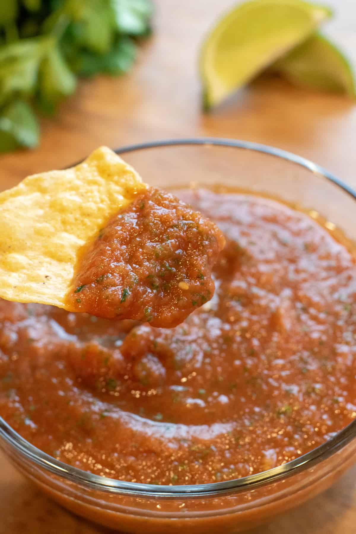 a chip with some salsa on it over a bowl of salsa.