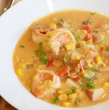 a bowl of shrimp chowder with corn red pepper and potatoes.