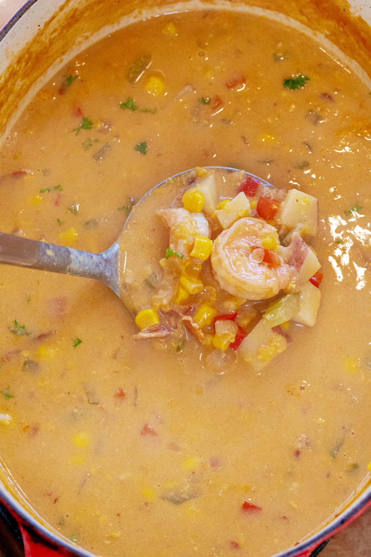 a ladle of shrimp chowder in a dutch oven.
